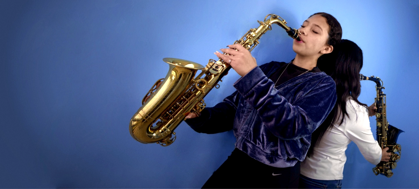 Dos estudiantes tocando el saxofón espalda con espalda